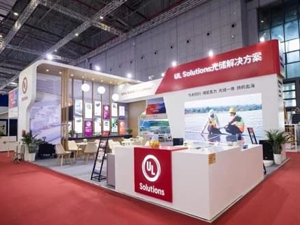 UL Solutions exhibition stand with red signage, product graphics and meeting seats
